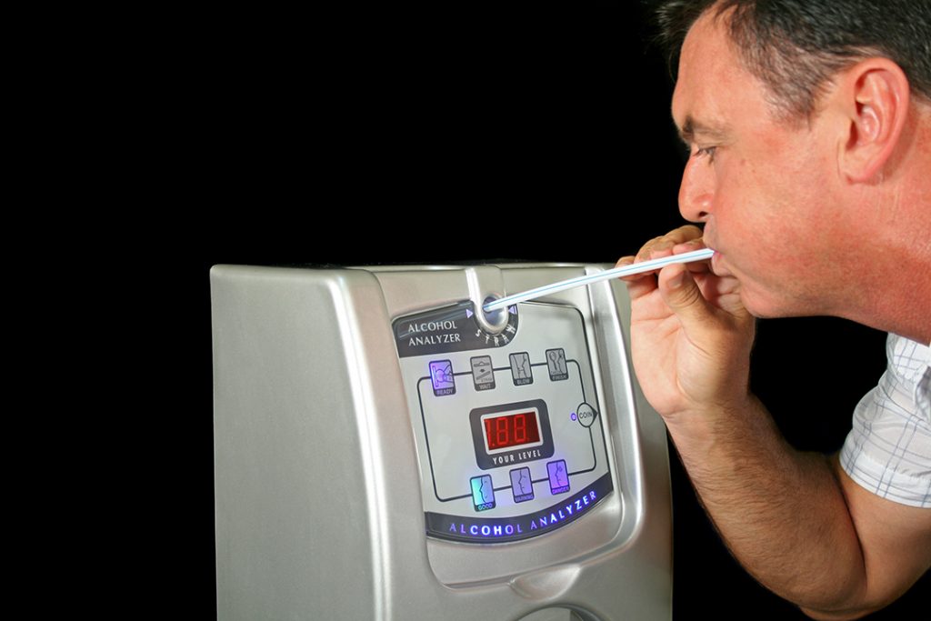 Man tests his alcohol level with a breath test machine.
